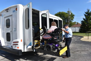 Driver uses lift to assist passenger in wheelchair to board a Dial-a-Ride bus